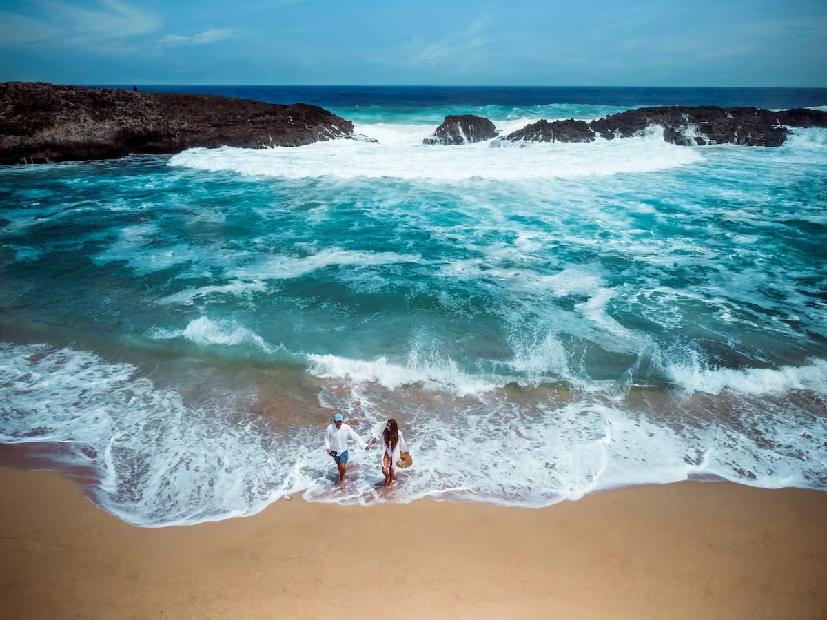 A couple walks along a wave-lapped Puerto Rico beach, minutes from La Palma House