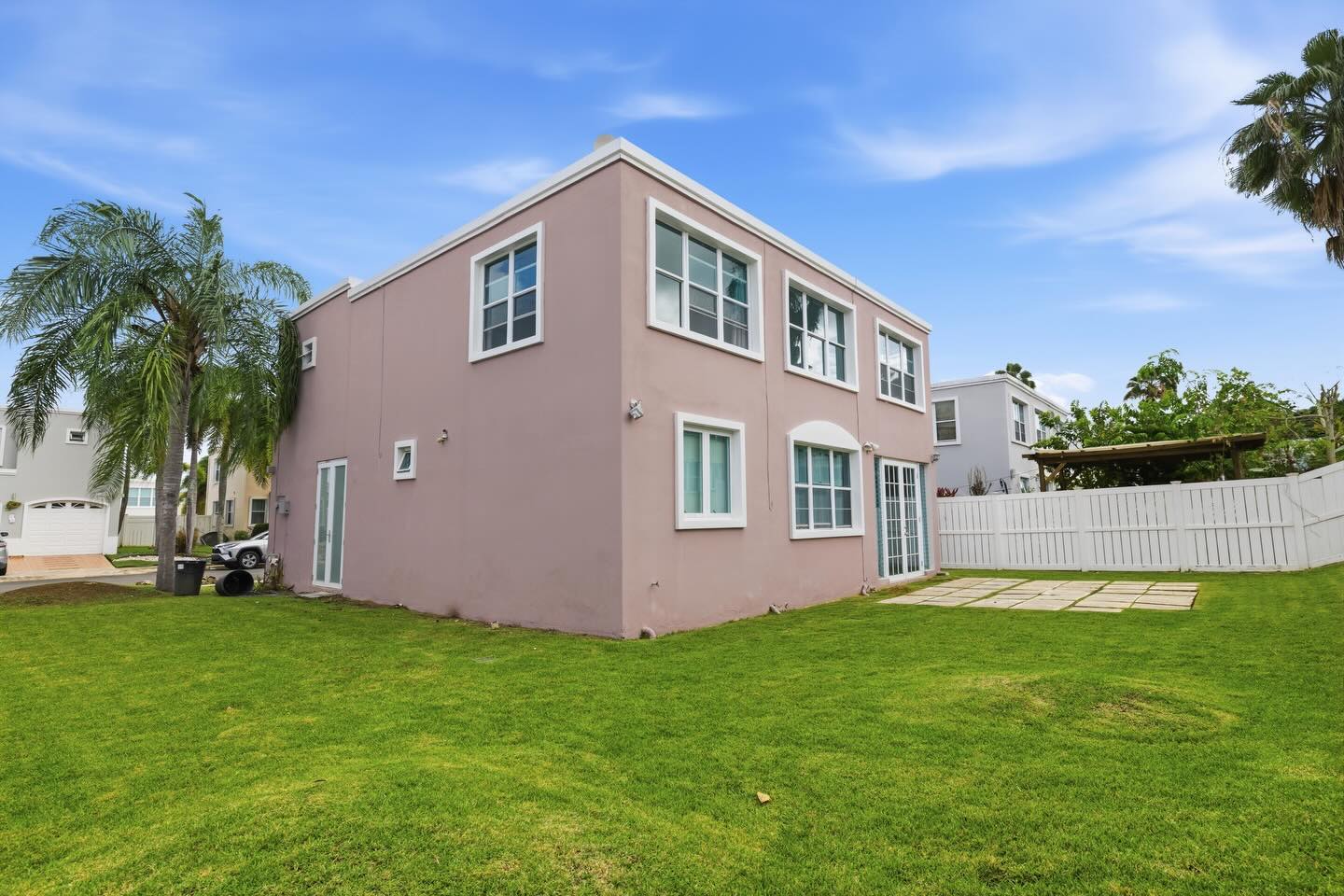 Side view of the pink townhome with a sunny yard